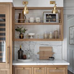 a kitchen with marble counter tops and wooden cabinets, gold accents on the upper shelves