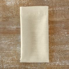 a white cloth folded on top of a wooden table with wood grains in the background