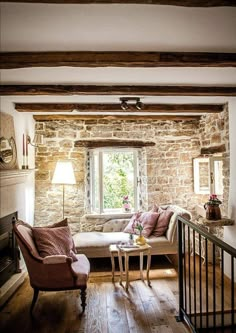 a living room filled with furniture and a fire place next to a window on top of a hard wood floor