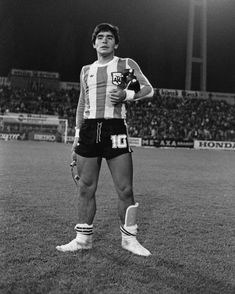 a man standing on top of a soccer field holding a ball in his right hand