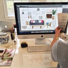 a woman sitting at a desk looking at a computer screen with architectural drawings on it