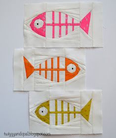 three fish made out of white fabric on top of each other with pink and yellow stripes