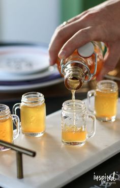 a person pouring honey into mason jars on a tray