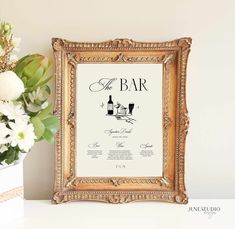 the bar is framed in an ornate gold frame next to flowers and a vase with white roses