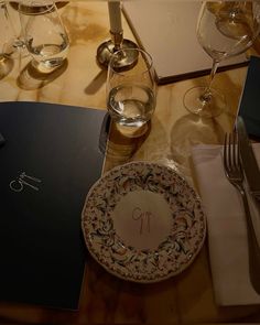 the table is set with wine glasses, silverware and place settings for two people