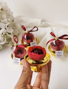 three red roses are in small glass vases with tags on them, sitting next to each other