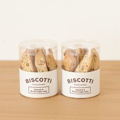 two glass jars filled with biscotti cookies on top of a wooden table next to each other