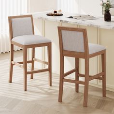 two wooden stools sitting next to each other on a kitchen counter with a marble top