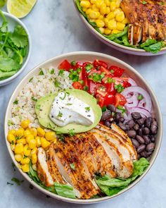 a bowl filled with chicken, rice, beans and avocado on top of a table