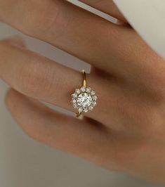 a woman's hand with a diamond ring on top of her finger and the other hand holding an engagement ring