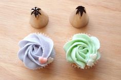 three cupcakes decorated with icing on top of a wooden table next to an egg