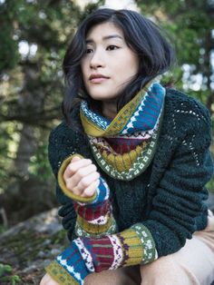 a woman sitting on the ground wearing a scarf