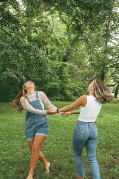 two young women holding hands in the grass