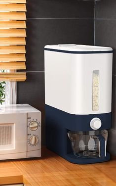 a white and blue coffee maker sitting on top of a wooden counter next to a microwave