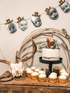 a table topped with cupcakes covered in frosting next to an antlers head