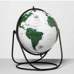 a white and green globe sitting on top of a metal stand with a black base