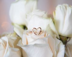 a heart shaped ring sitting on top of white roses