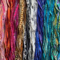 many different colored scarves are stacked together