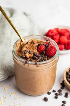 a glass jar filled with chocolate pudding and topped with raspberries next to other desserts