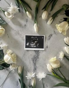 white flowers arranged in a circle on a marble surface with a black and white photo