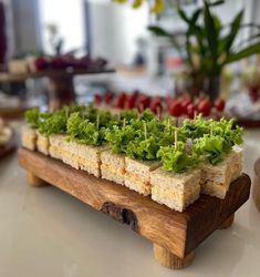 a wooden tray filled with food on top of a white table next to a potted plant