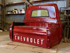 an old red chevrolet truck in a garage