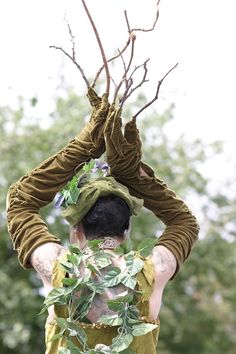 a man with tattoos on his body and arms, wearing a costume made out of leaves