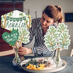 a woman arranging flowers in vases on top of a table with the words, we are family