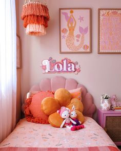 a bedroom with pink walls and pictures on the wall above the bed, along with two stuffed animals