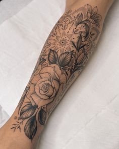 a woman's arm with flowers and leaves on it