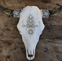 a cow skull with some beads on it's horns is displayed against a wooden wall