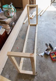 some tools are laying on the floor in front of a wooden frame that is being built