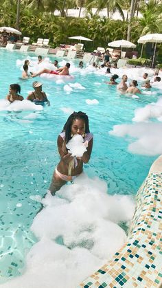 a woman standing in the middle of a swimming pool surrounded by clouds and umbrellas