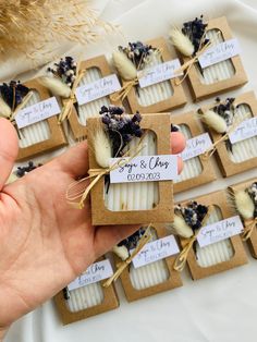 a person holding some kind of soap in front of small boxes with dried flowers on them