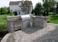 an outdoor bbq with grill and sink in the middle of a brick patio area