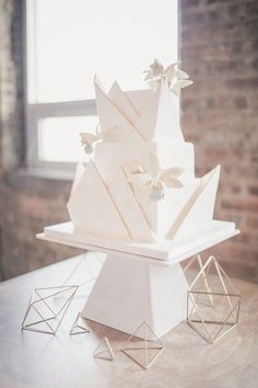 a three tiered white cake sitting on top of a wooden table