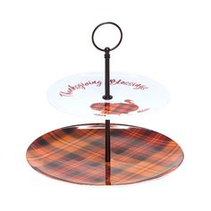 an orange and black plaid cake stand with two plates on it, each holding a serving plate