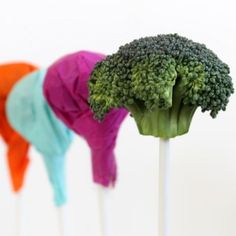 broccoli sticks with different colors on them in the shape of hats are lined up