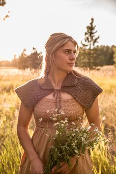 a woman standing in a field holding flowers