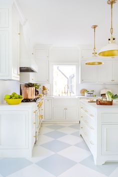 a white kitchen with checkered flooring and yellow lights hanging above the countertop