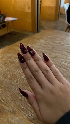 nail inspo. red medium length almond nails. red & black ombre with hand painted gold star Nails Acrylic Almond Red And Black, Red Nail Fall Design, Vampire Nails Coffin, December Nail Inspo Almond, Maroon Almond Nails Design, Cancun Mexico Nails, Dark Red Wedding Nails, Star Designs On Nails, Deep Red Holiday Nails