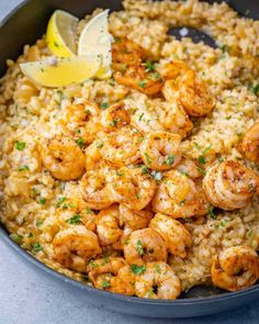 shrimp and rice in a skillet with lemon wedges on the side for garnish