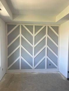 an empty room with white painted walls and grey chevroned panels on the wall