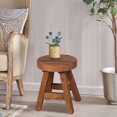 a small wooden stool next to a potted plant