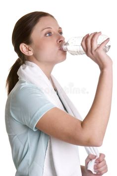 a woman drinking water from a bottle while holding a towel around her neck stock photos