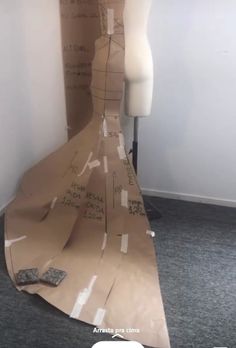 a mannequin made out of cardboard sitting on top of a floor next to a wall