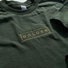 Embroidered onto a 100% cotton garment with a golden thread for a classic look. Soft-washed and garment-dyed as a forest green, the t-shirt makes for a durable staple and memento of Jungkook's first solo endeavor. This will be the softest tshirt you own! Please refer to the size guide in the listing for shirt measurements. If you have any questions or if there's a specific size/shirt color you would like but it's out of stock, please message me! I'll try my best to accommodate :) Relaxed Fit Gold Cotton Top, Gold Short Sleeve Cotton Shirt, Gold Cotton Short Sleeve Shirt, Gold Cotton Top With Relaxed Fit, Gold Crew Neck Cotton T-shirt, Gold Crew Neck Cotton Top, Gold Cotton Crew Neck Top, Green Long Sleeve T-shirt With Embroidered Logo, Casual Gold Cotton T-shirt