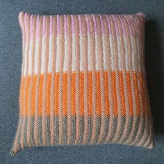 an orange and white striped pillow sitting on top of a blue couch next to a wall