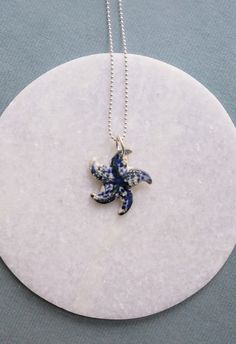 Ceramic seastar made by hand with love from strong stoneware clay. Al glazes turn out different every time so every piece of jewelry is unique. This piece has a shiny white glaze with cobalt blue details on it.  The standart silver-plated ball-chain necklace is 52 centimeters long around the neck but you can choose your own length Blue Necklaces With Starfish Charm For Gifts, Ocean-inspired Silver Necklace With Star Charm, Blue Sterling Silver Necklaces With Starfish Charm, Blue Sterling Silver Necklace With Starfish Charm, Blue Starfish Sterling Silver Necklace, Ceramic Fish Necklace, Sea Pottery Necklace, Blue Sterling Silver Starfish Necklace, Blue Star-shaped Nickel-free Necklace