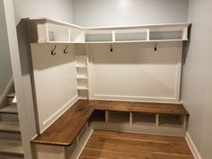 an empty room with white walls and wooden benches on the bottom floor, along with shelves